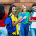 Laughing mexican female student showing thumb up with group of students outdoor at campus of university